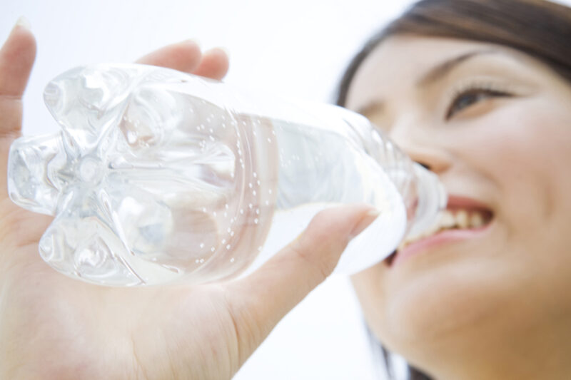 ペットボトルの水で水分補給をする女性
